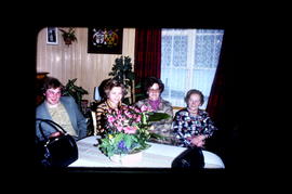 [Quatre femmes assises autour d'une table fleurie]